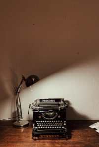 alte Schreibmaschine mit eingeschalteter Lampe, turned-on desk lamp near calculator